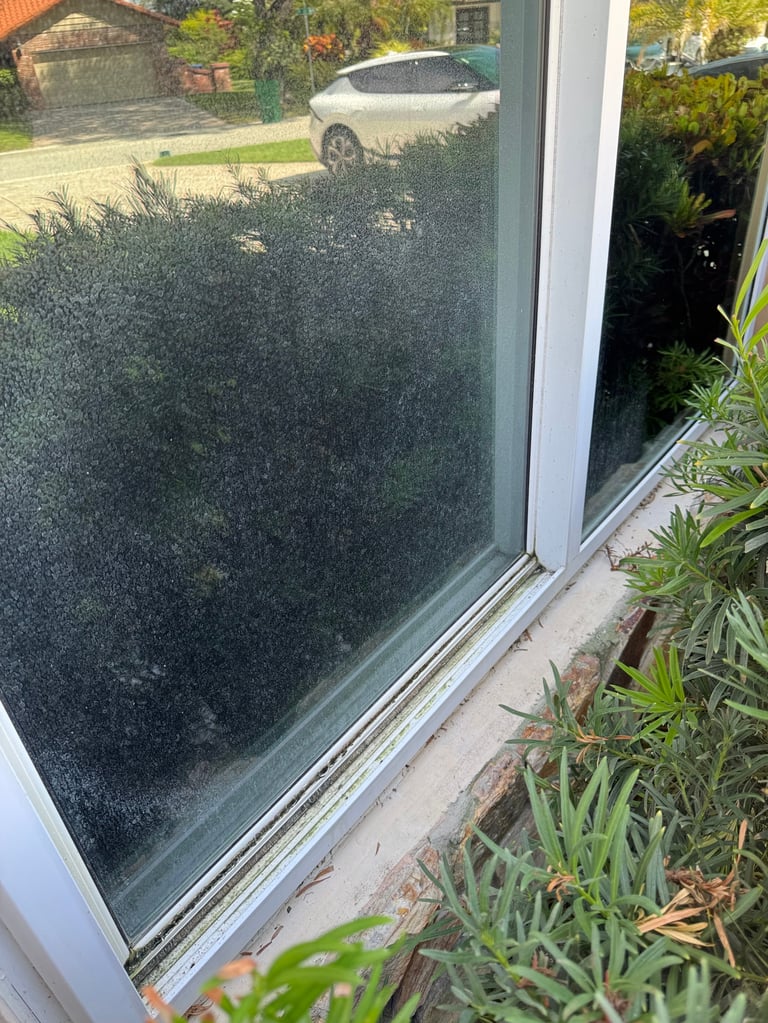 Large frosted glass window showing condensation before professional hard water stain removal treatment at a South Florida home
