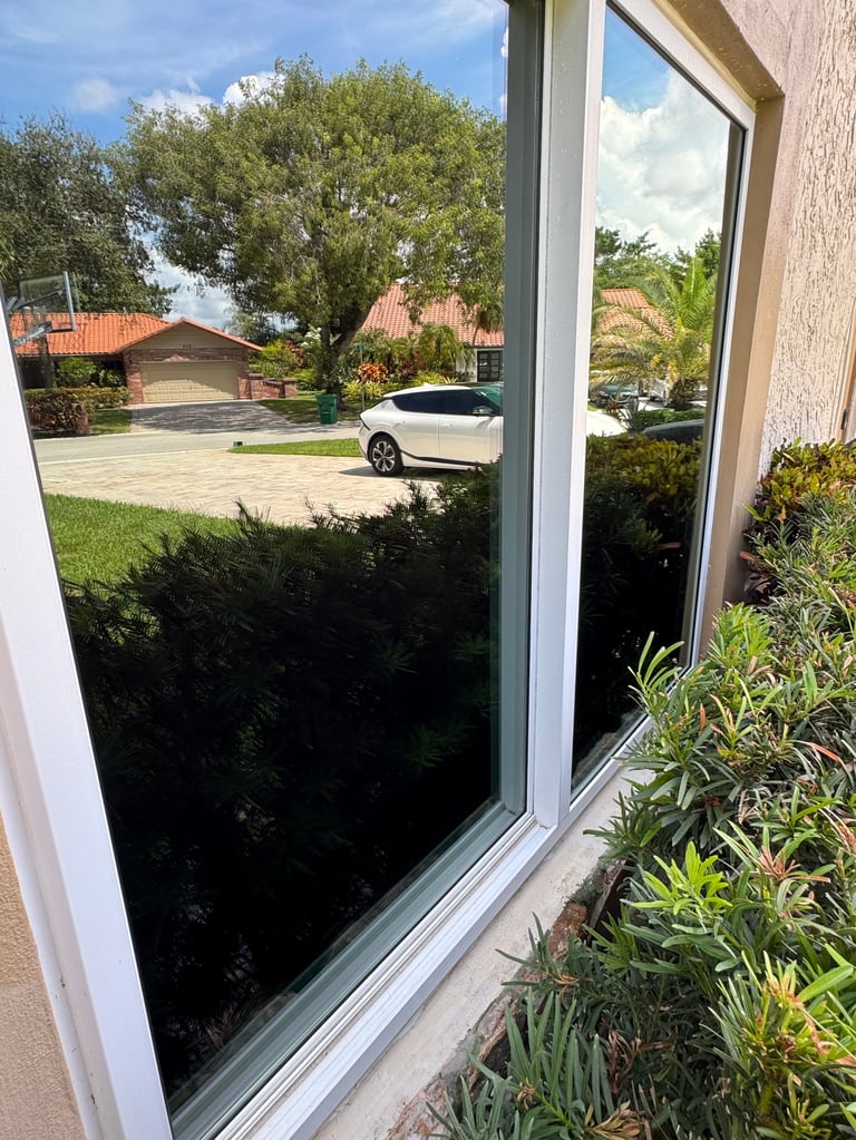View through a freshly cleaned large window of a residential driveway with white car and garage in South Florida