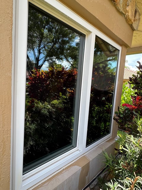 Freshly cleaned white-framed windows on a tan stucco home in Boca Raton after professional window cleaning service